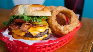 a cheeseburger and onion rings in a red basket