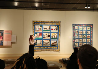 woman points to quilt on the wall MMA